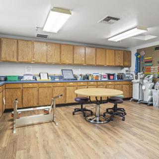 An organized classroom with tables, chairs, and wooden cabinets.