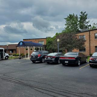 A view of a brick building with a parking lot filled with cars under a cloudy sky.