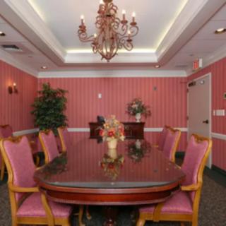 An elegant dining or meeting room featuring a chandelier and classic pink decor.