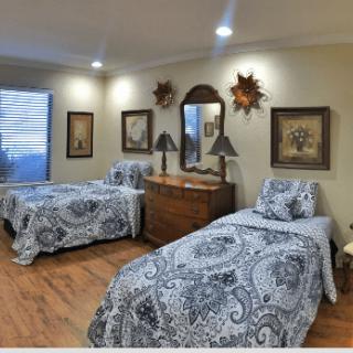 A cozy bedroom featuring twin beds with patterned bedding, elegant lamps, and decorative artwork.