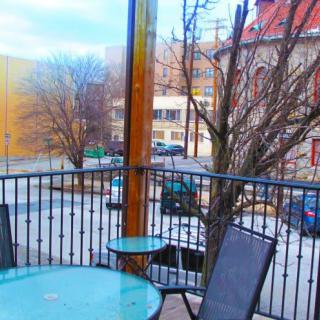 A cozy outdoor patio with chairs and a table overlooking an urban street scene.