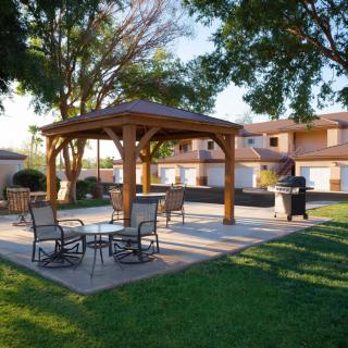 A cozy outdoor patio with a gazebo, surrounded by trees and greenery.