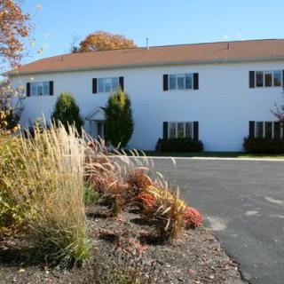 A residential apartment building with surrounding landscaping, including grasses and trees.