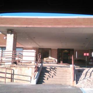 A view of the entrance to a building with steps and railing.