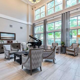 A modern living room with a grand piano, featuring large windows and ample natural light.