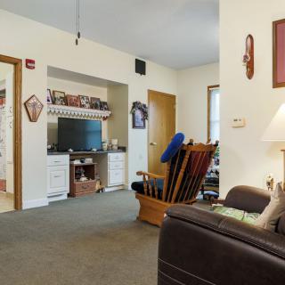 A cozy living room with a television, sofa, and rocking chair, adorned with various decorations.