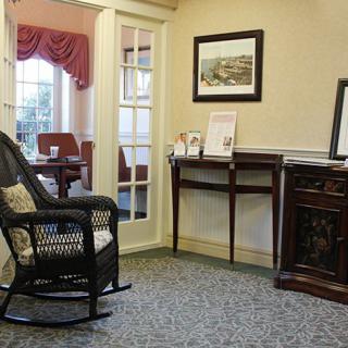 A cozy waiting area featuring a rocking chair, traditional furniture, and framed artwork.