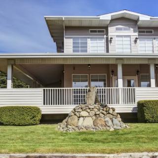 A two-story house with a spacious front porch and well-maintained lawn.
