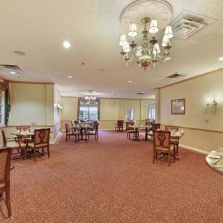 A spacious dining area with elegant decor, featuring a chandelier and multiple tables set for guests.