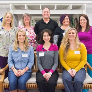 A cheerful and diverse team gathered for a group photo in an office setting.