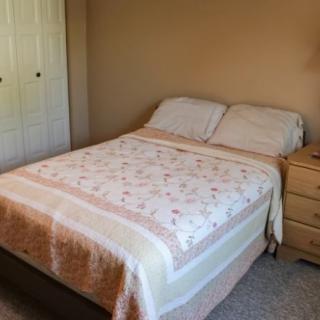 A neatly made bed in a cozy bedroom with a nightstand beside it.
