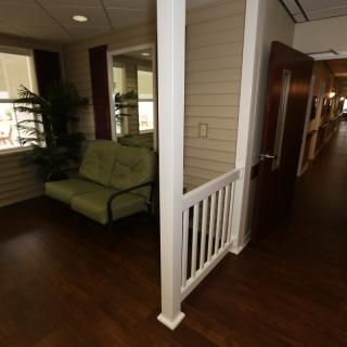 A cozy seating area with a sofa is situated in a hallway with wooden floors and decorative elements.