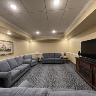 A cozy living room with comfortable sofas, a large television, and soft lighting.