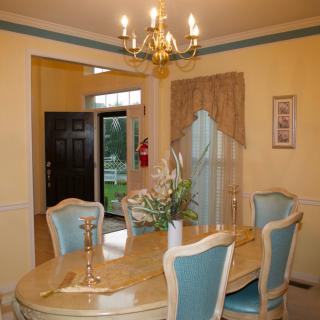 A traditional dining room with a chandelier, table, and upholstered chairs.