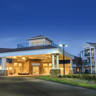 A well-lit building entrance with surrounding landscaping at night.