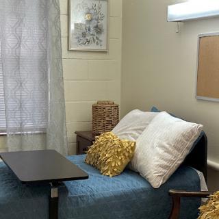 A cozy bedroom setup featuring a bed with decorative pillows, a small table, and soft lighting.