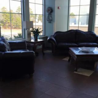 A cozy living room with leather sofas and a coffee table, surrounded by large windows.