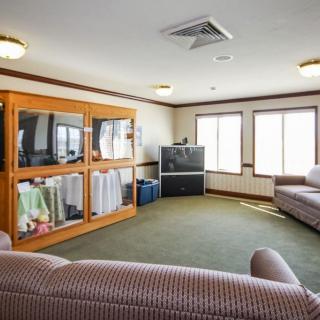A cozy living room with sofas, a television, and shelves filled with items.
