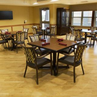 An empty dining room with neatly arranged tables and chairs on a wooden floor.