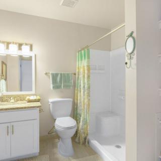 A clean and bright bathroom with a toilet, sink, and shower area.