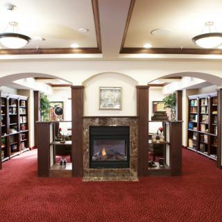 A cozy library interior with a fireplace and surrounding bookshelves.