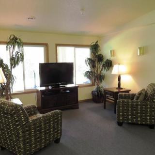 A cozy living room with comfortable chairs, a TV, and large windows allowing natural light to brighten the space.