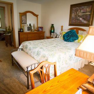 A cozy bedroom with a neatly made bed, wooden furniture, and decorative items.