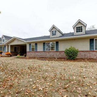 Single-story house with brick and siding exterior surrounded by a leaf-covered yard.