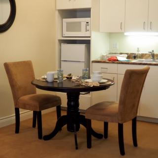A cozy dining area with a small round table and two chairs, adjacent to a kitchenette equipped with a microwave and refrigerator.