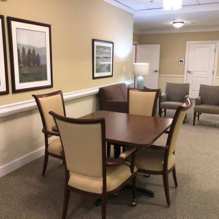 A well-appointed waiting room with a table, chairs, and framed artwork on the walls.