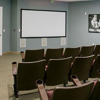 A small home theater room with rows of chairs facing a blank projector screen.