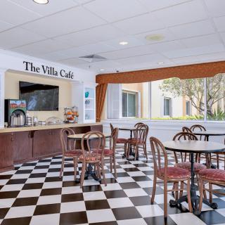 A cozy cafe with checkered flooring and multiple tables and chairs, creating a welcoming atmosphere.