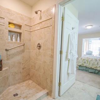 A modern bathroom with a tiled shower area and an adjacent bedroom.