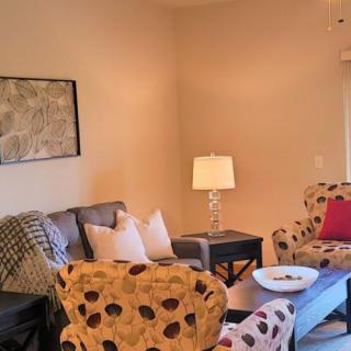 A cozy living room with patterned armchairs, a sofa, and a decorative lamp.