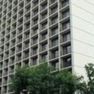A tall building with a grid of windows, surrounded by trees.