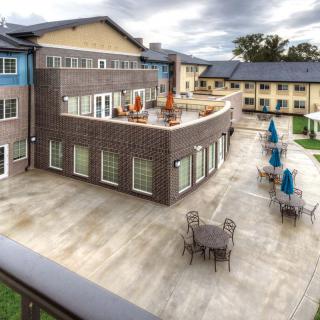 A modern apartment complex featuring a spacious patio with outdoor seating.