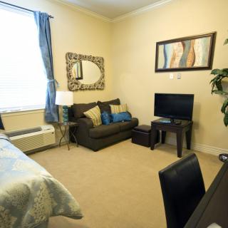 A cozy apartment living room featuring a sofa, television, and decorative artwork.