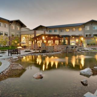 A scenic view of a hotel with a pond reflecting the illuminated building facade during the evening.