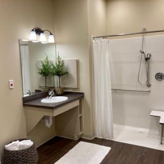 A modern, accessible bathroom with a sink and large shower area.