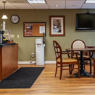 A cozy office break room with tables, chairs, a water cooler, and a TV on the wall.