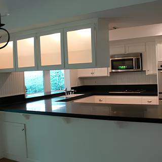 A modern kitchen with sleek white cabinets and a dark countertop.