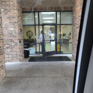 A person stands outside a building entrance, waiting to enter through the glass doors.