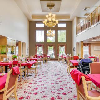 A spacious dining area with red tablecloths, elegant chandeliers, and large windows.