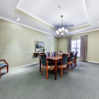 A spacious dining room with a long wooden table, surrounded by chairs and illuminated by a chandelier.