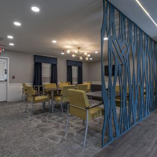 A modern dining area with yellow chairs and a decorative partition.
