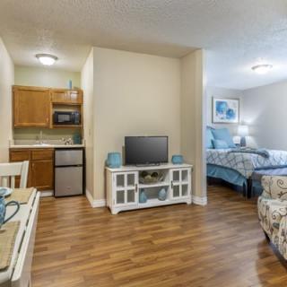 A cozy studio apartment with a kitchenette, television, and comfortable bedroom.