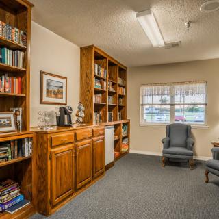 Cozy library room with wooden bookshelves and armchairs.