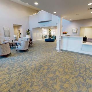 A spacious and well-lit lobby with a reception desk, comfortable seating, and indoor plants.