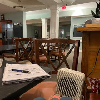 A cozy workspace featuring a table, chairs, and a small heater in a relaxed environment.