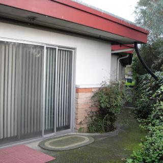 An exterior view of a house showcasing sliding doors and a landscaped garden.
